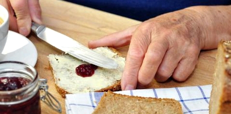 Eine Seniorin schmiert ein Brot