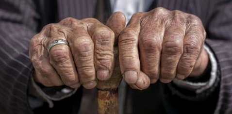 Die Hände eines alten Mannes halten einen Stock