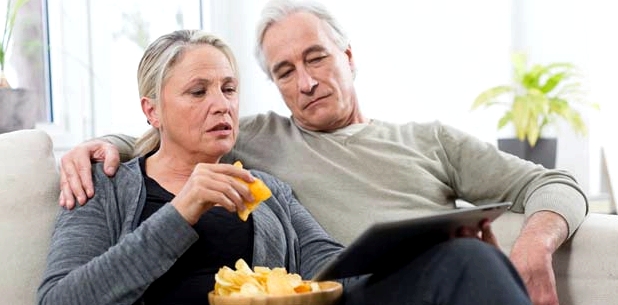 Paar isst Chips auf Couch - Gift für die Leber