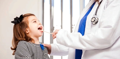 Kinderarzt untersucht den Mund eines Mädchens