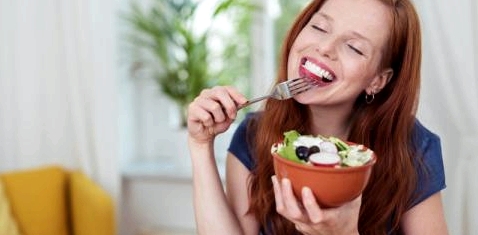 Eine Frau isst genüsslich Salat