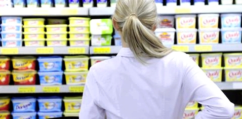 Eine Frau steht vor einem Supermarktregal und denkt nach
