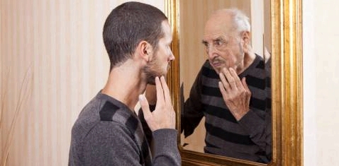 Junger Mann blickt auf sein altes Spiegelbild
