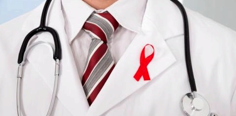 Ein Arzt trägt eine Aidsschleife am Kittel