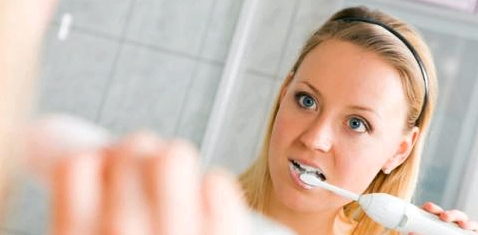 Frau putzt Zähne gegen Zungenbelag